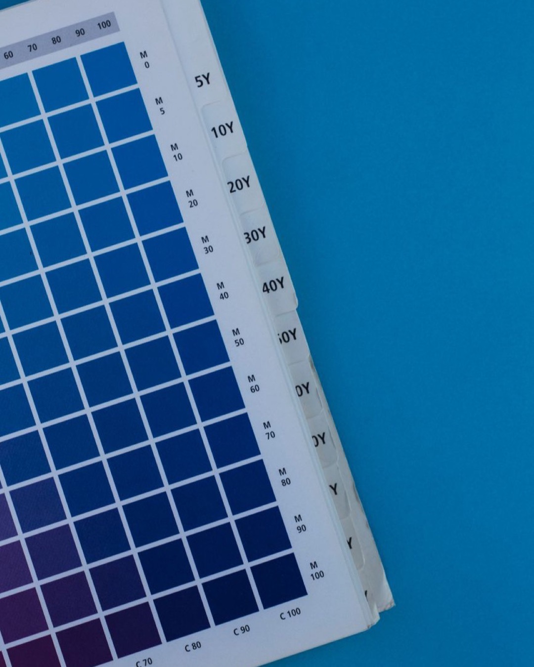 Close-up of a blue gradient color palette on paper against a blue background.