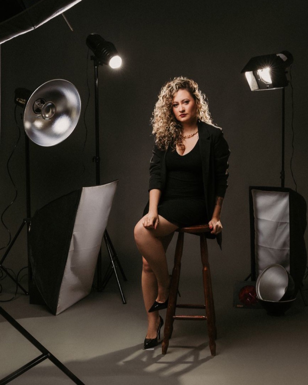 Fashion model in a studio setting wearing a blazer and heels, showcasing style and elegance.