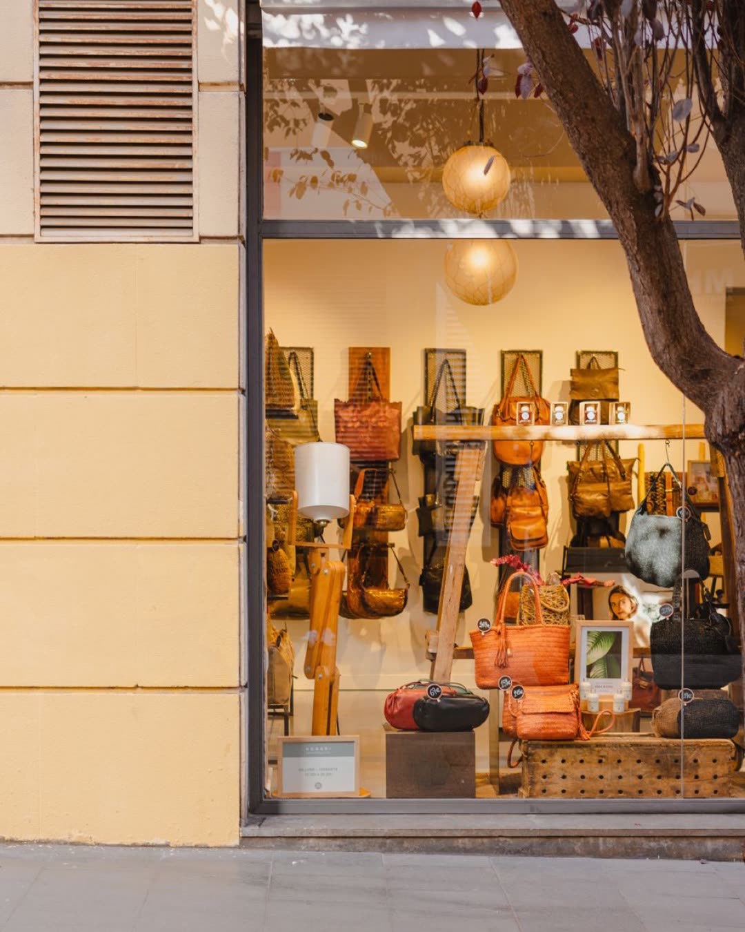 Elegant handbag store display in Barcelona, featuring a variety of stylish bags through a large glass window.