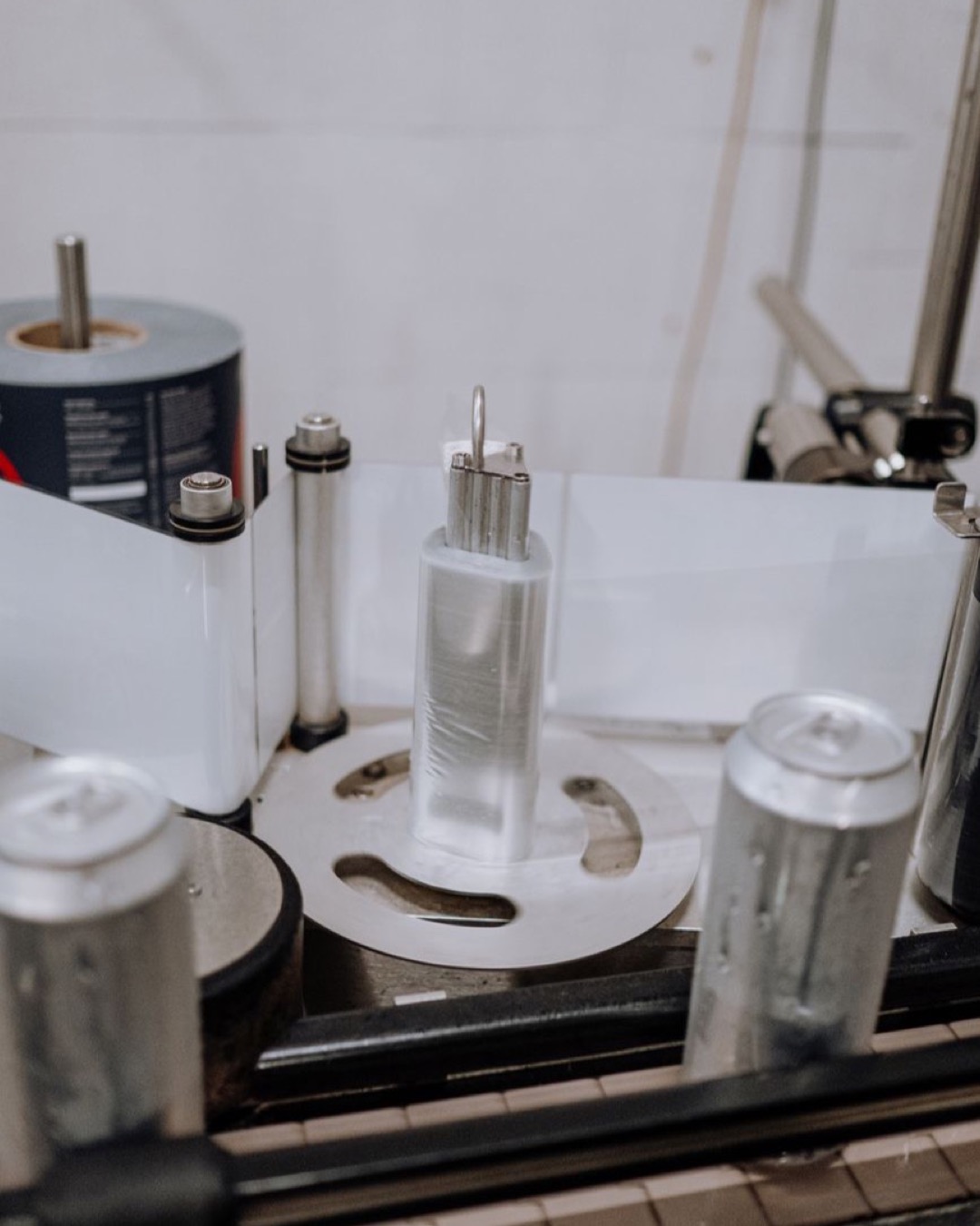 Close-up of an automated system labeling beverage cans in a modern brewery factory.