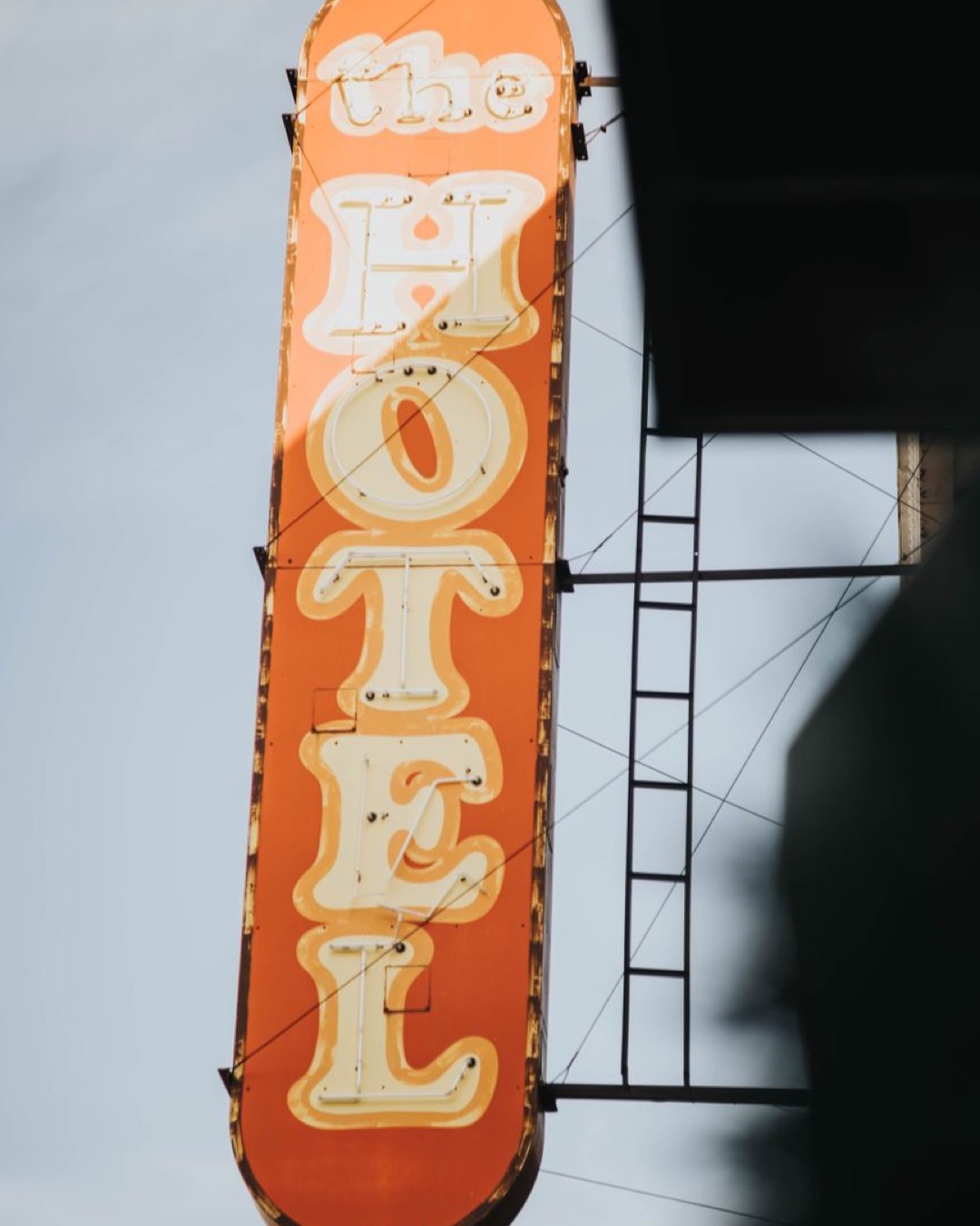 Vintage hotel sign with bold text against a clear blue sky, capturing retro travel vibes.