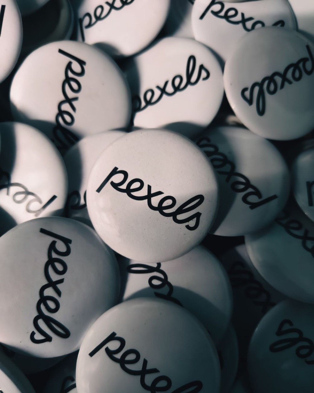 Close-up view of white Pexels logo buttons in shadowy lighting, creating a moody and artistic composition.