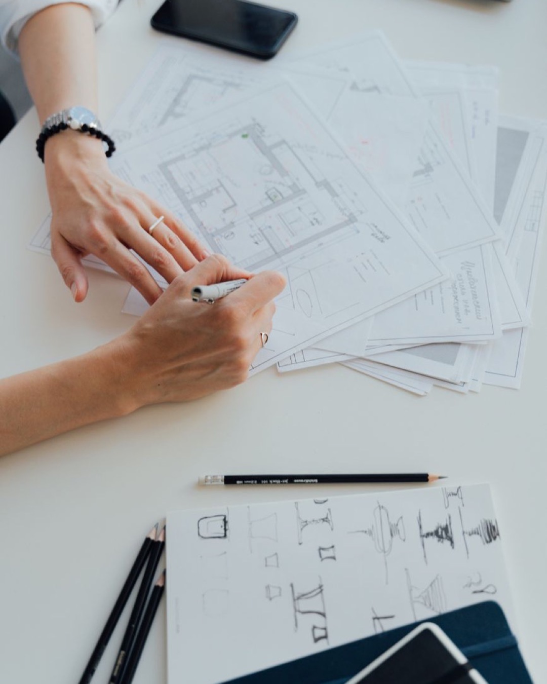 High angle view of architectural floor plans and paperwork on a wooden desk in an office setting.
