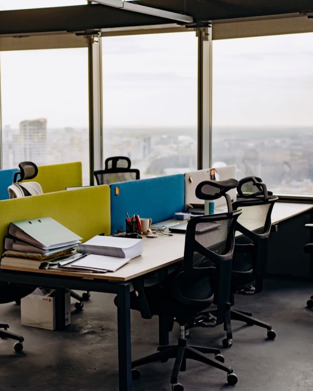 Open office space with colorful dividers and a city view, typifying modern urban work environments.