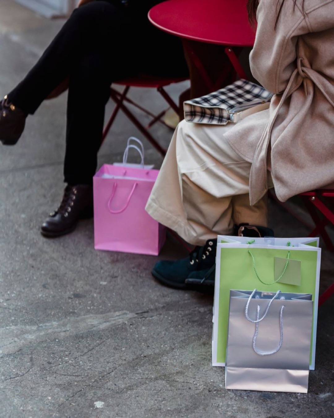 High angle of female friends sitting at table of outdoor cafe with colorful shopping packets