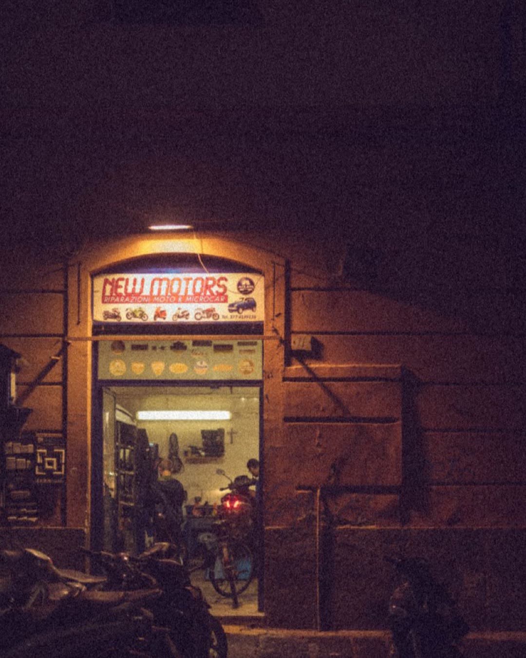 Dimly lit motorcycle shop entrance at night, showcasing vintage ambiance and urban charm.