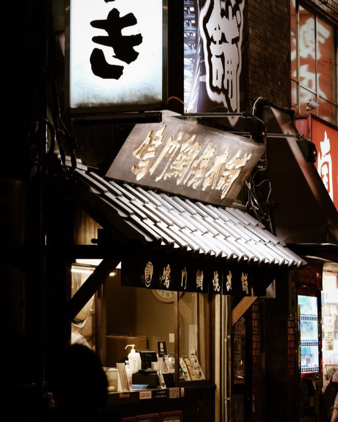 Illuminated storefronts and glowing signs in Shinjuku at night, capturing urban Tokyo's vibrant atmosphere.