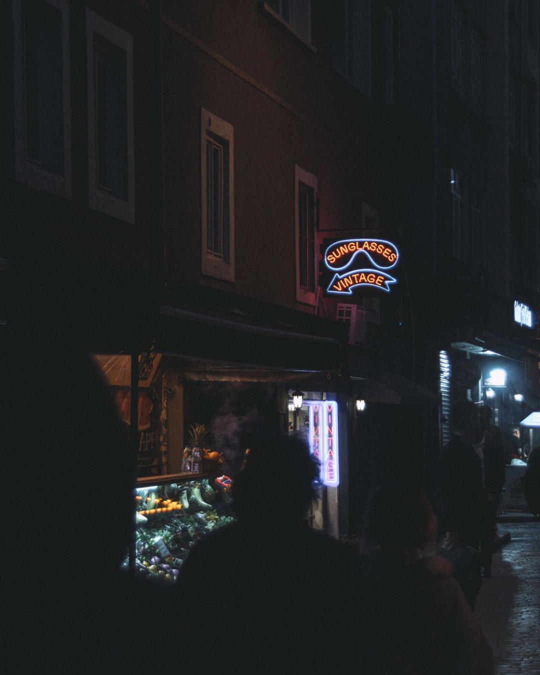 Moody urban street scene at night with illuminated neon signs and vibrant nightlife atmosphere.