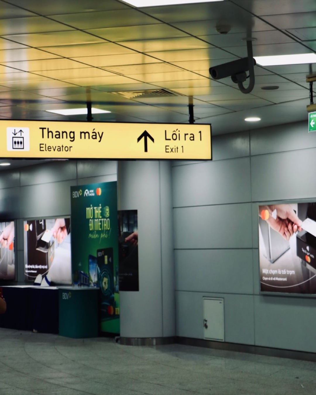 Metro station interior with signage for elevator and exit in Vietnamese and English.