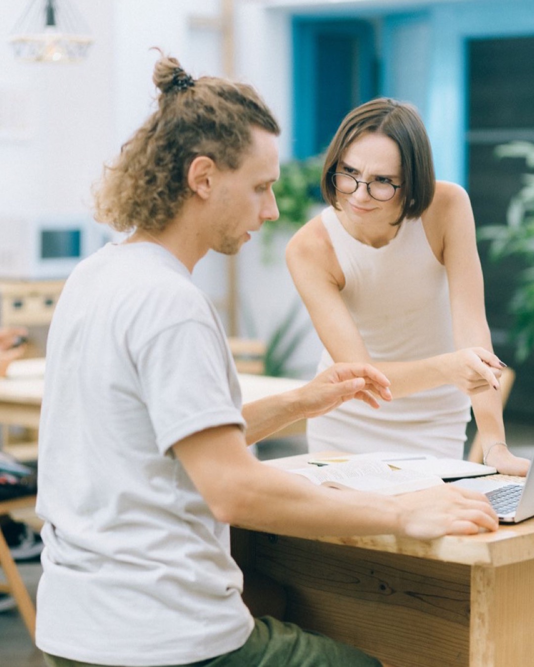 Two coworkers discussing a project in a modern open office space.