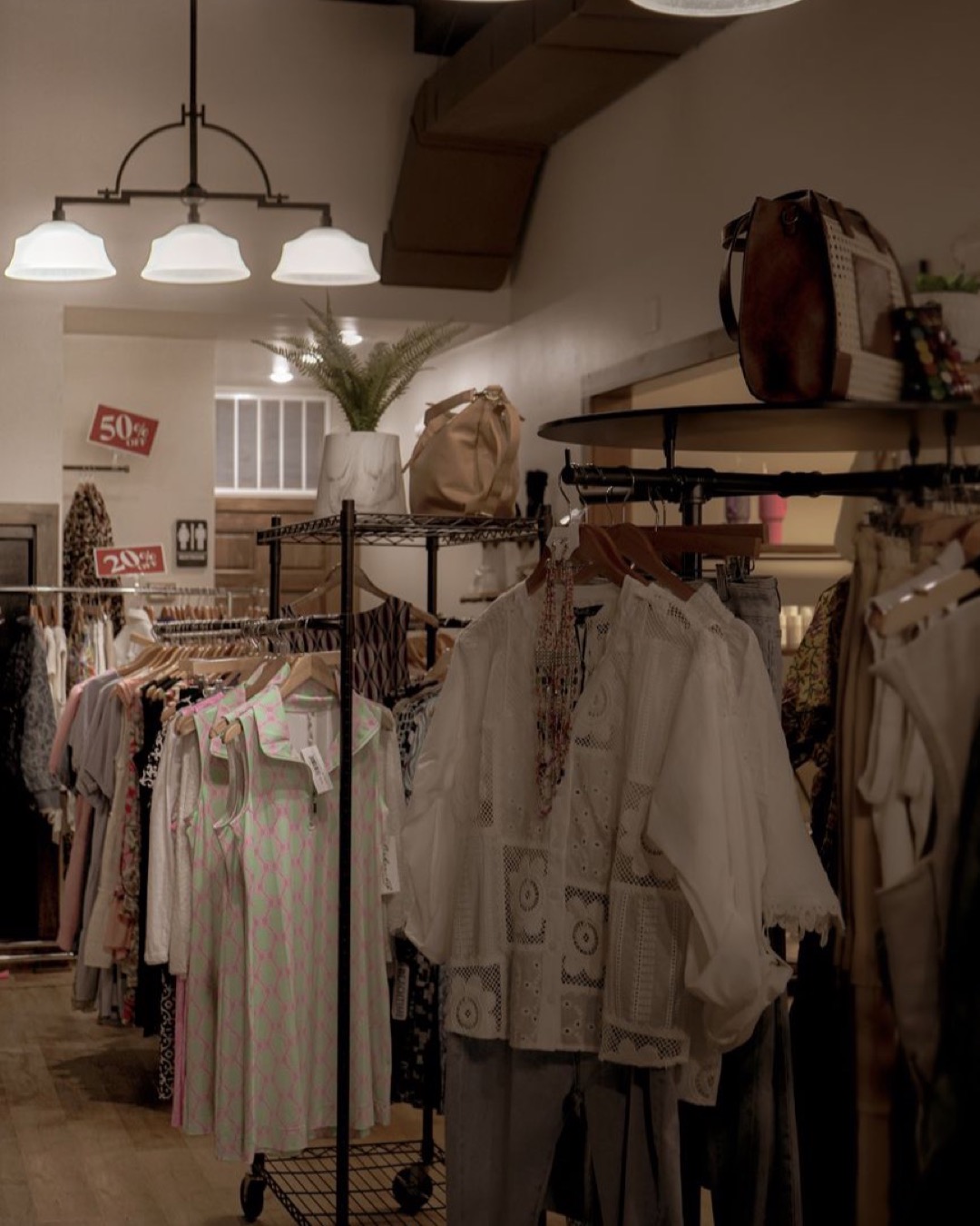 Warm and inviting boutique interior showcasing elegant fashion on racks under stylish lighting.