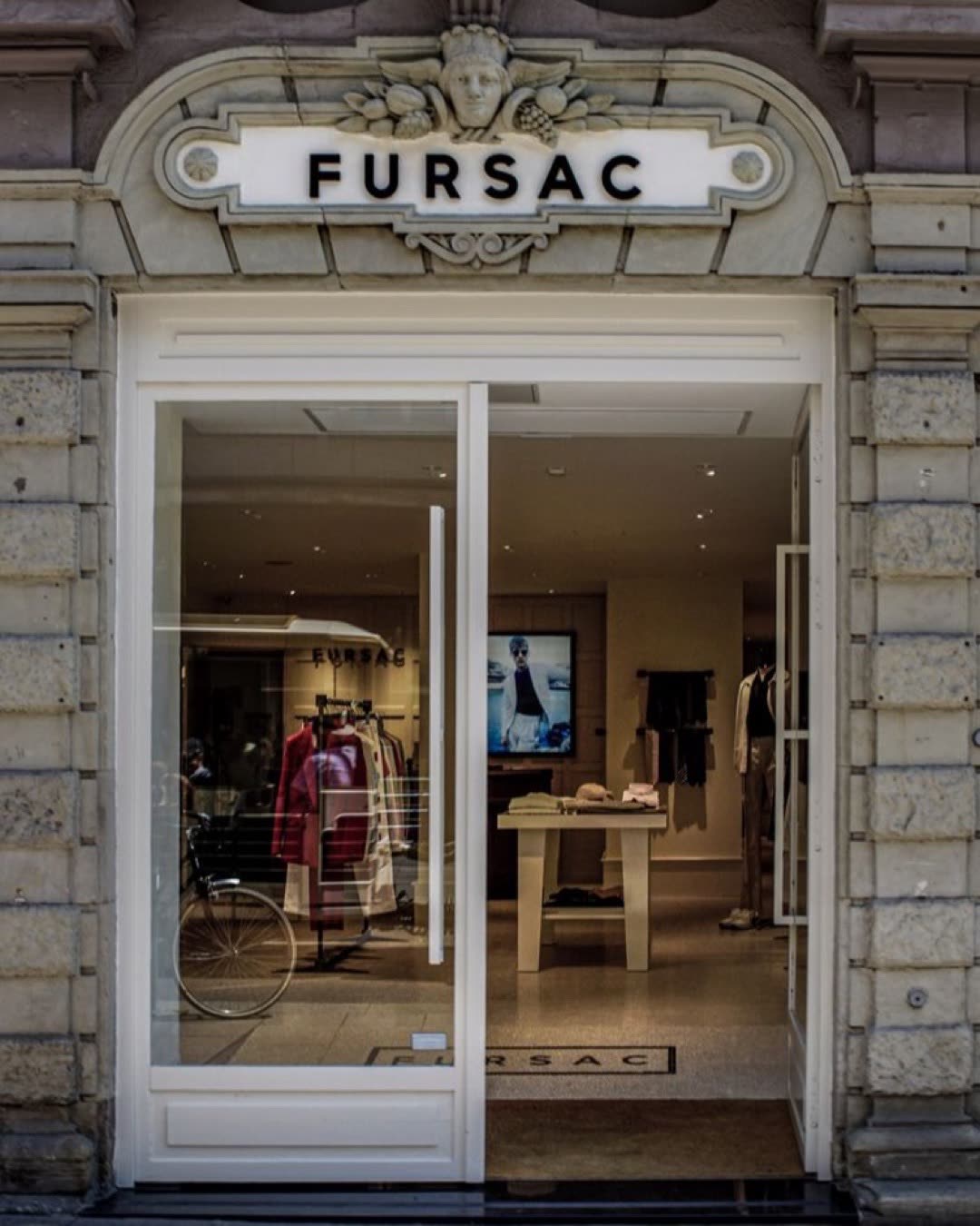 A stylish entrance to a luxury clothing store featuring elegant architecture and fashion displays.