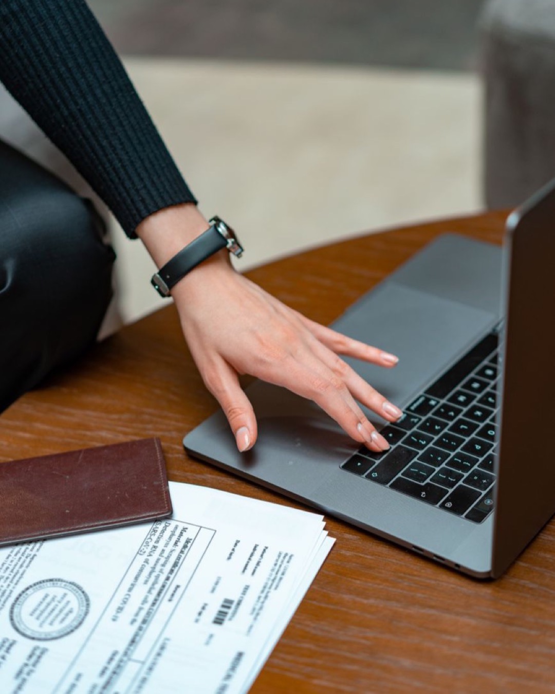 Close-up of a person typing on a laptop with legal documents on a table, showcasing work and technology integration.