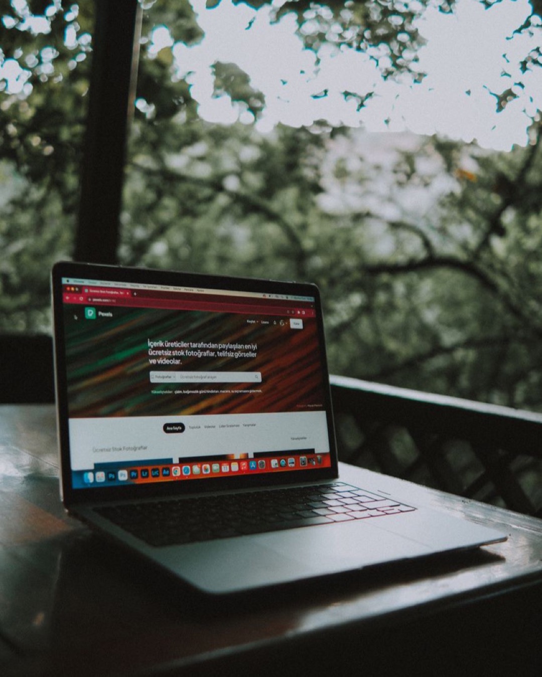 Open laptop showing a website screen on a wooden table in an outdoor terrace setting.