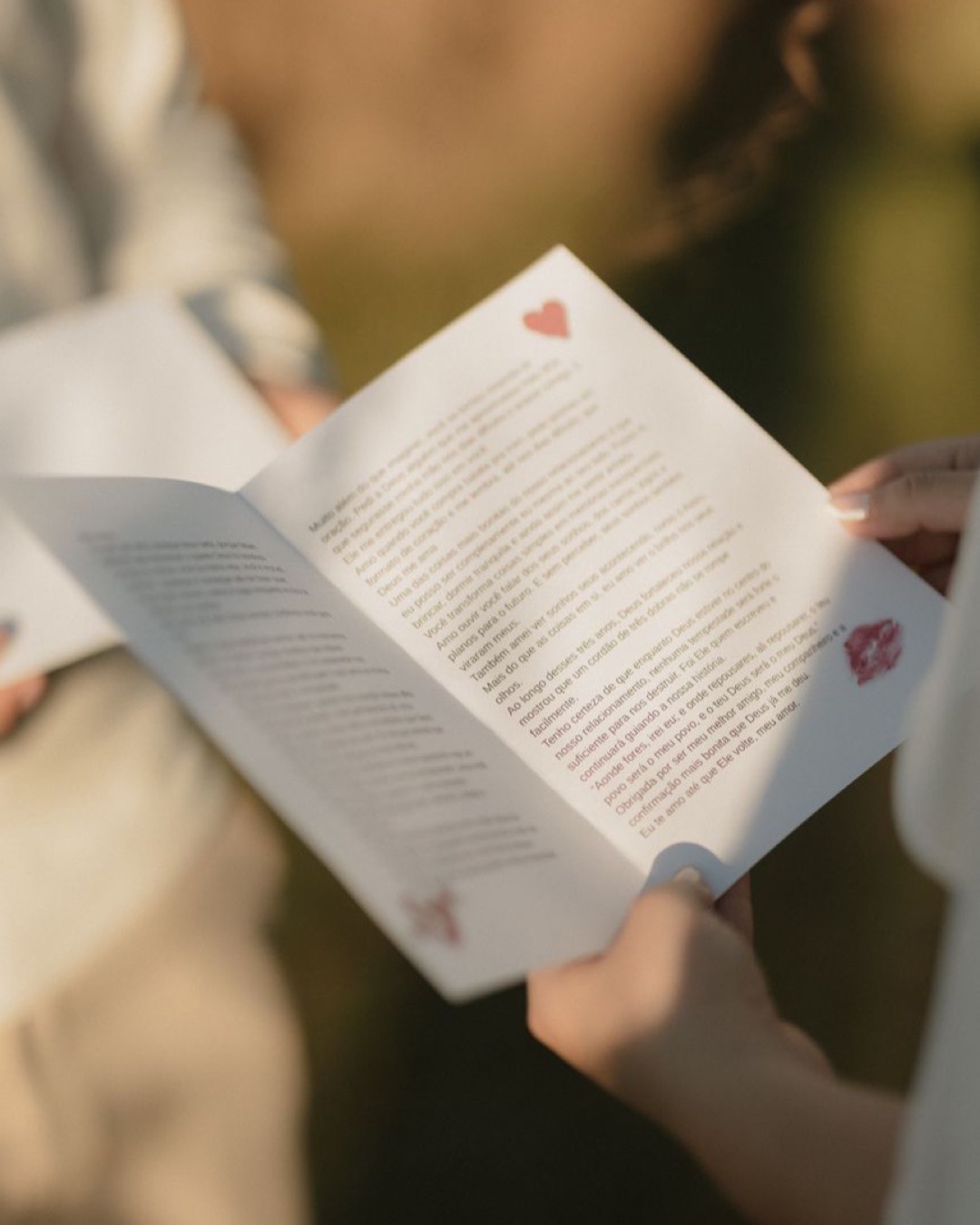 Two people exchanging romantic letters outdoors, captured in soft sunlight.